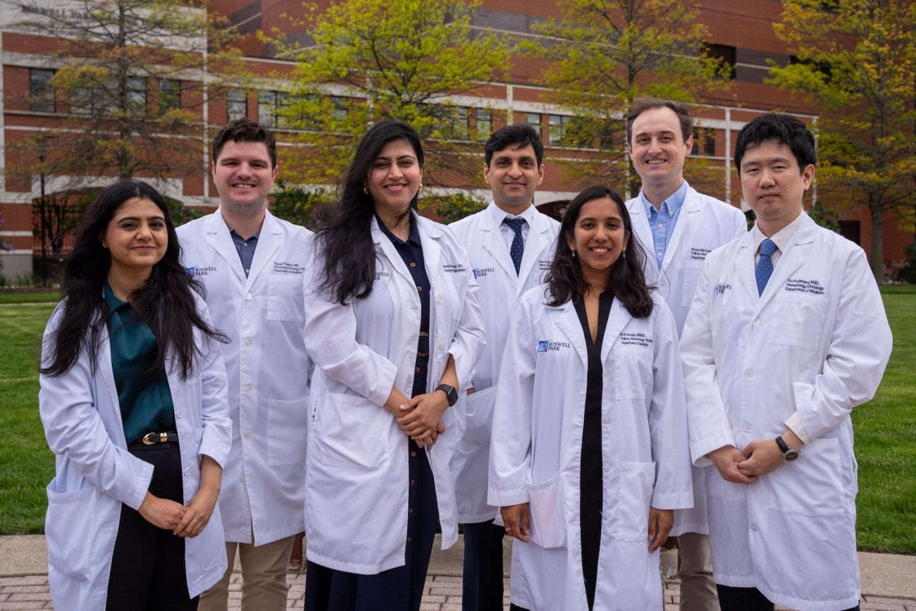 Seven graduating fellows of the hematology oncology fellowship program smile at the camera in Kaminski Park - 2026