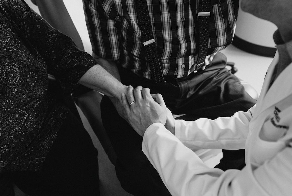 Dr. Dhir holds hands with a patient and his wife