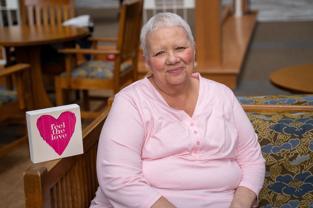 SallyAnn Decker, a Roswell Park ovarian cancer patient, sits in the lobby next to a sign that reads "feel the love"