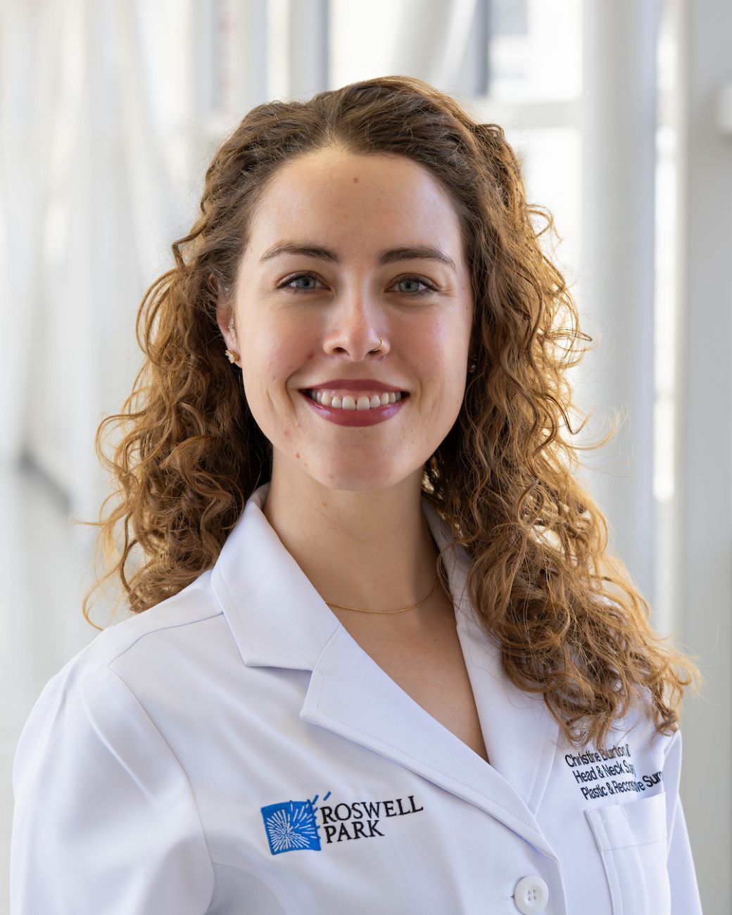 A woman in a white doctor's coat with curly red hair