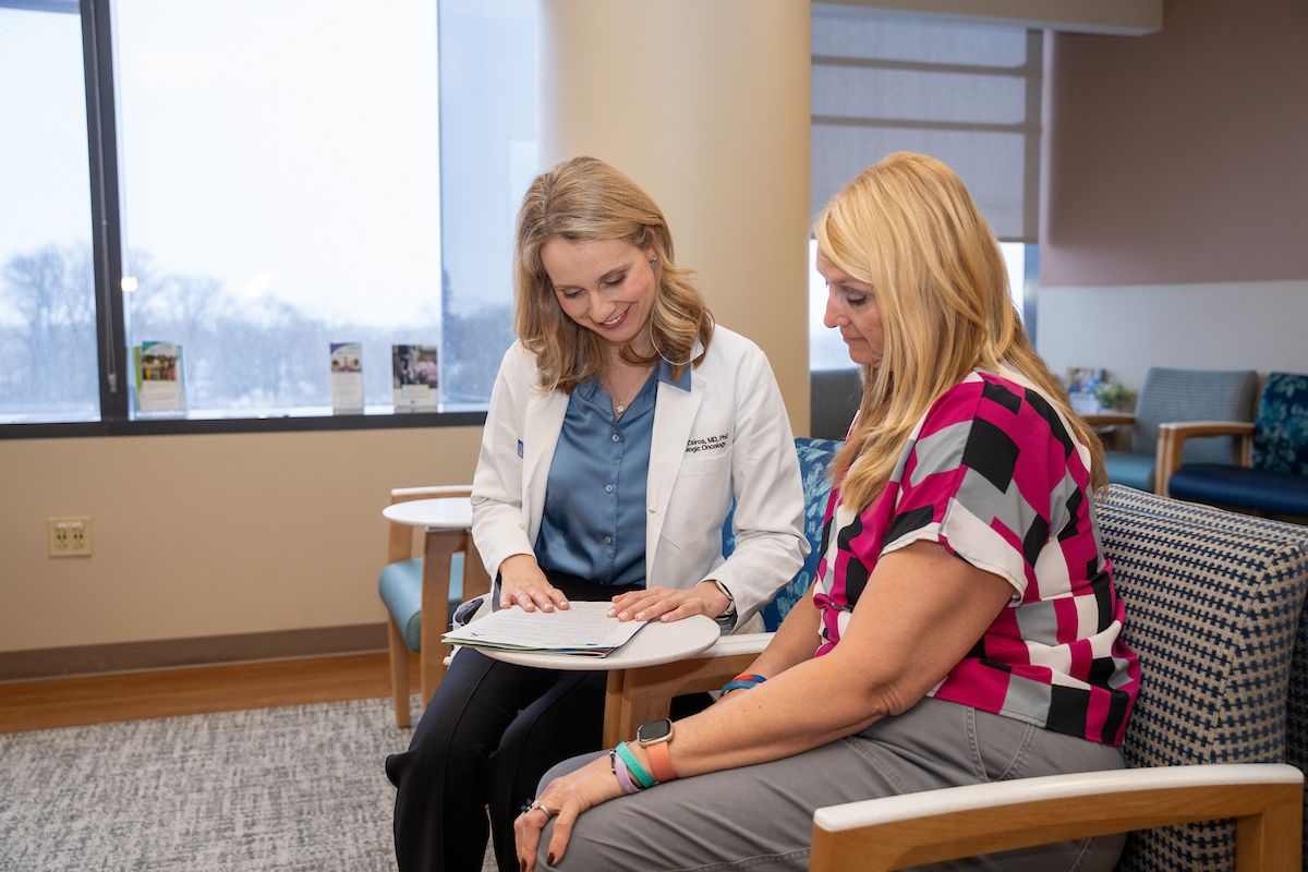 Dr. Emese Zsiros sits with a patient in the GYN waiting room reviewing a file
