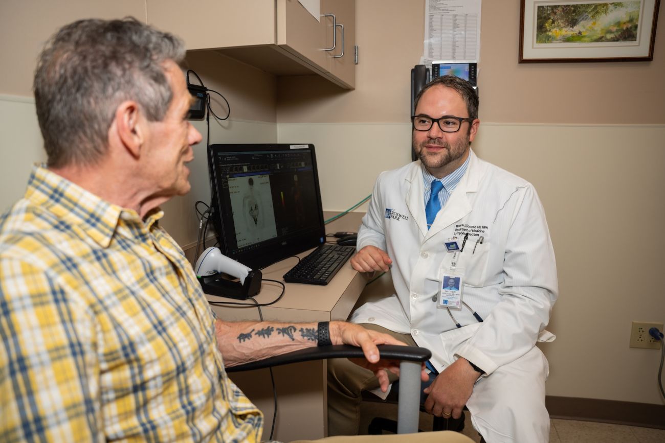 A doctor speaks with an elderly man in an exam room