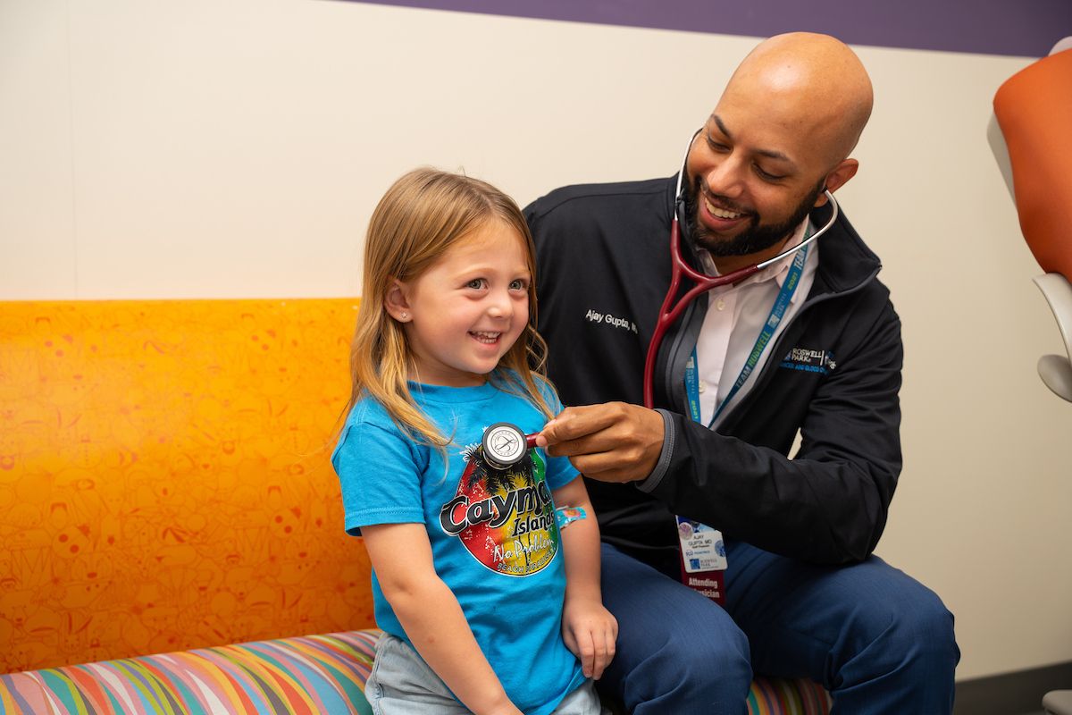 Dr. Aja Gupta uses a stethoscope on a young patient