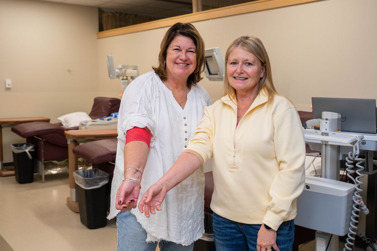 Two women smile with their arms extended after donating blood at the Donor Center
