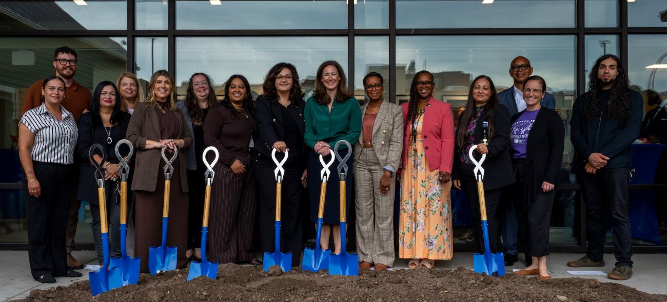 A group of people stand behind shovels at a groundbreaking