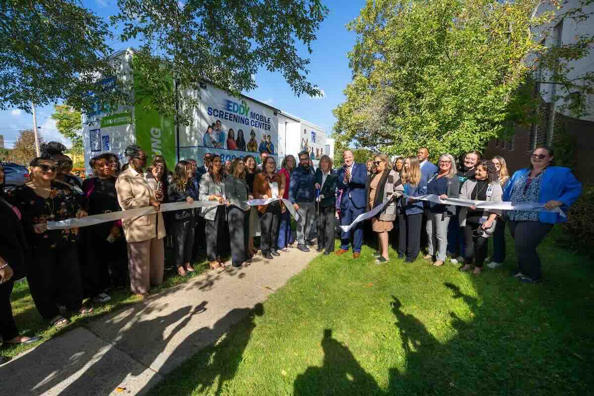 Group of leaders gather in front of new mobile screening unit to cut ribbon