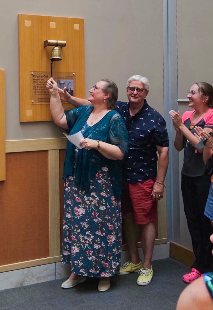 AML patient Frankie Ciezki rings the Victory Bell with her husband Robb and family cheering her on