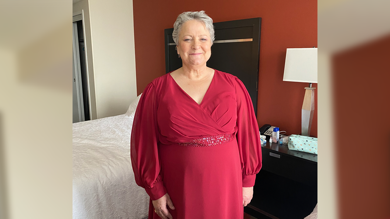 Cindy Mantai, breast cancer Care Network patient, smiles in a red dress