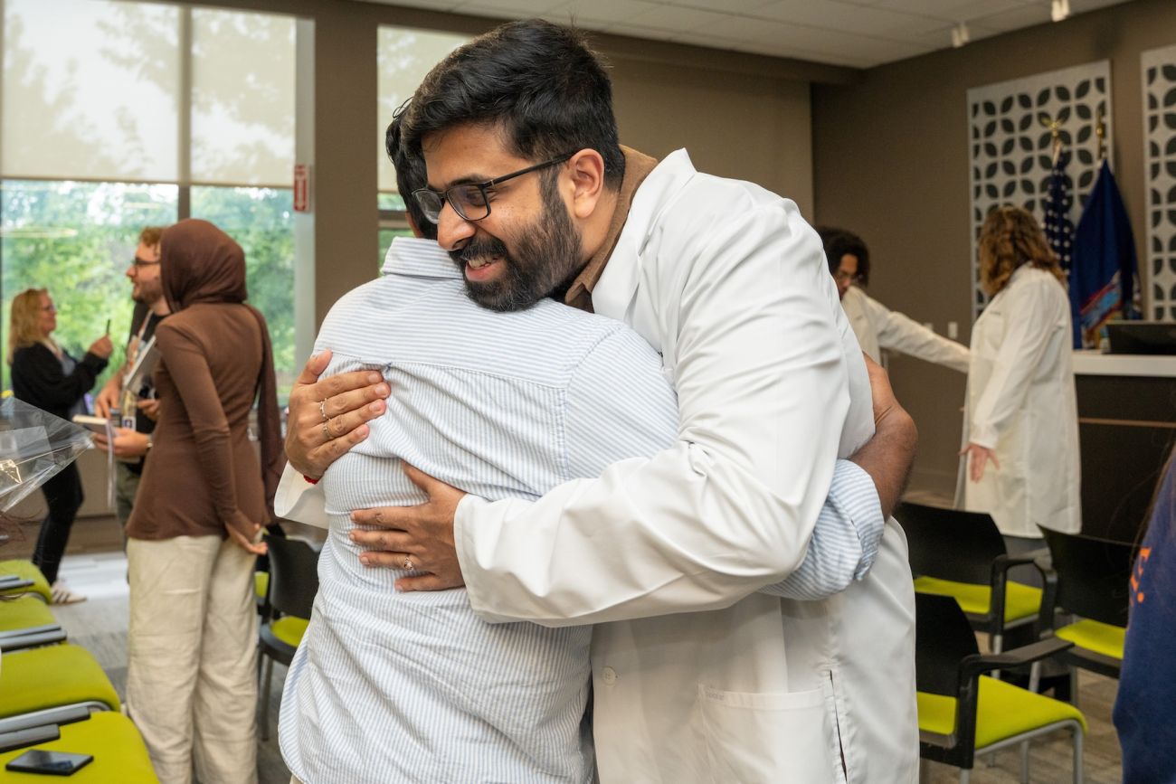 A recent graduate hugs their mentor