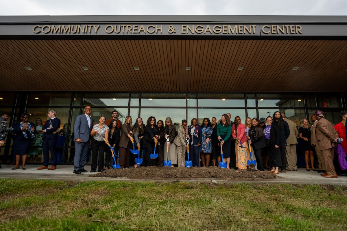 Un grupo de personas se reúne para la ceremonia de colocación de la primera piedra frente al número 907 de Michigan.