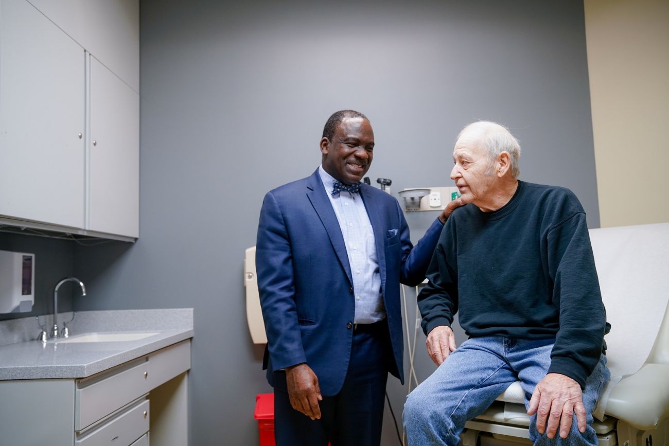 Dr. Chumy Nwogu smiles along with patient in exam room