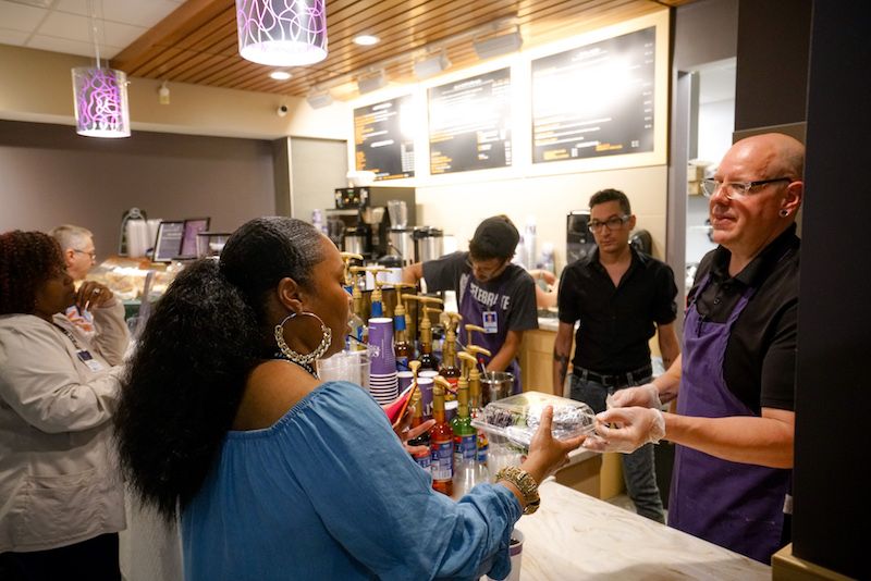 A woman receives her food from a barista at the coffee shop in the lobby of Roswell Park.