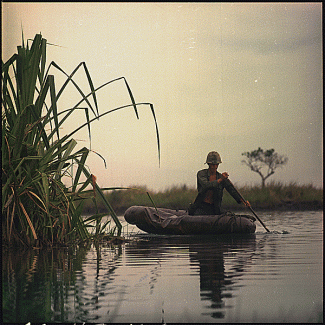 US Army private paddling in an inflatable boat in a river in Vietnam, 1968