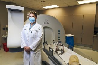 Dr. Lindsay Lipinski stands in front of Gamma Knife radiosurgery equipment