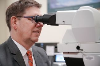 Dr. Charles Levea looking through a microscope to confirm a diagnosis.