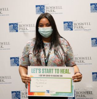 Woman holding a sign stating that she got vaccinated to protect her family, her patients and herself