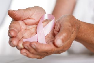 Woman's cupped hands holding pink cancer ribbon