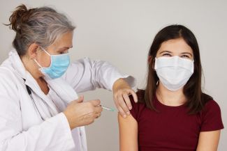 Doctor administers vaccine to adolescent girl.