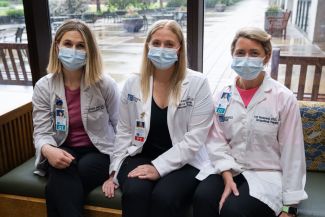 Three Roswell Park lymphedema therapists in white coats sit on a couch. 