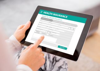 Person using a tablet to compare health insurance plans