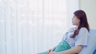 Patient sitting up in bed looking out a window