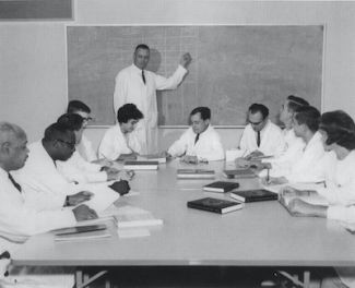Old photo of a doctor teaching at a blackboard