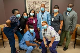 Eight people in scrubs smiling behind their surgical masks represent the Phlebotomy Department at Roswell Park. 