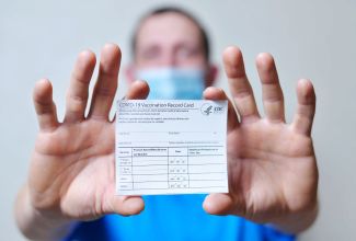 vaccination card held by a masked man