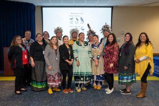 Members of Roswell Park's Center for Indigenous Cancer Research join dancers wearing traditional Indigenous costumes. 