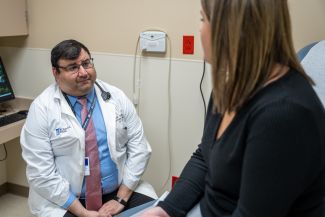 Dr. Deepak Vadehra sits in clinic with a patient