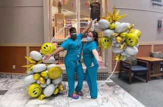Two nurses in front of a balloon display