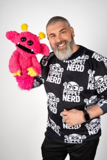 Adam Kreutinger holds a pink puppet, Hubble. 
