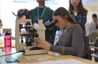 A student in the BHE program looks through a microscope