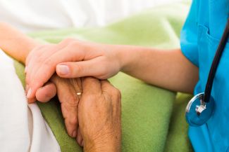 Elderly person holding hands with a medical professional