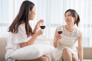 Two young women talking while holding glasses of wine