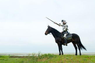 Person wearing medieval armor riding a horse